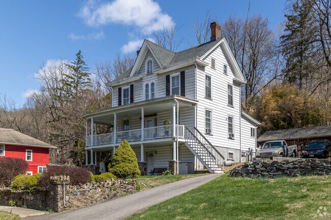 Glen Gardner home features a steep roofline, double porch, and a long driveway up the hill.