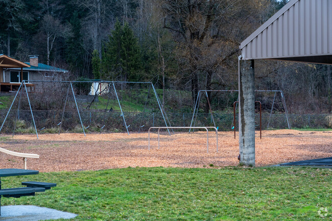 A swing set sits next to a covered basketball court.
