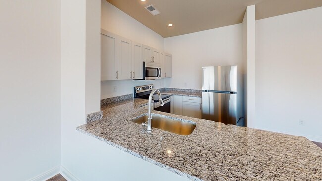 The Alred kitchen features granite countertops, a breakfast bar, and stainless steel appliances.