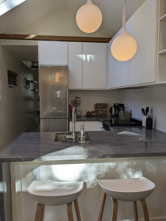 Fully equipped kitchen has natural stone countertops, stainless appliances, and garbage disposal.