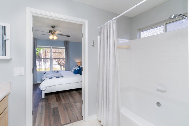 A nice wide soaking tub with a shower along with a medicine cabinet, towels, toiletries.