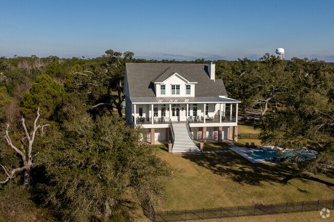 A large raised farmhouse style home sits across the street from the water in Pass Christian.