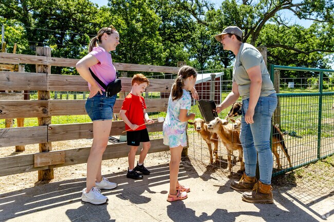 Children feed friendly goats at Primrose Farm under the watchful eyes of adults.