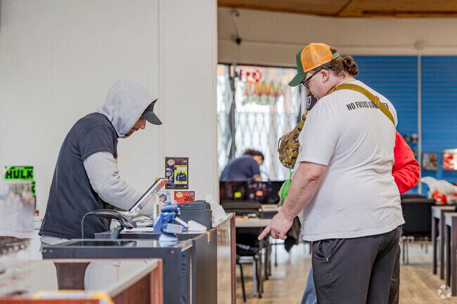 Patrons at Comiks the Gathering purchase items at the front counter.