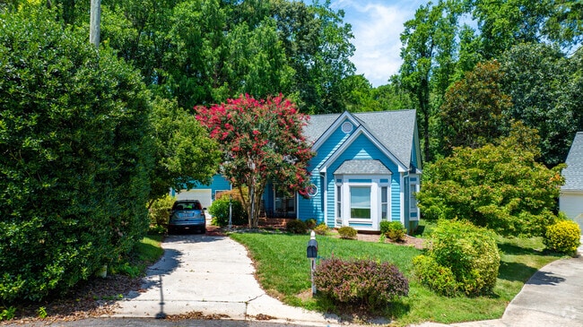 This Cape Cod–inspired home in Stonehenge East features well kept greenery and a private drive.