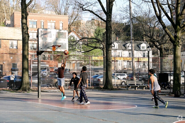 Van Cortlandt Park residents enjoying a game of basketball with friends on a nice day.