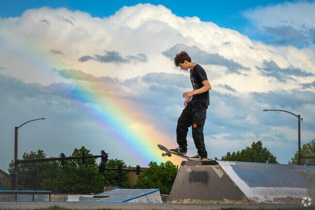 Beneath a rainbow arcing over Trail Winds Skate Park—just minutes from Lewis Pointe—a skater carves through the curving bowl, wheels humming in sync with summer light. Every twist, every grind, feels like a splash of color and freedom on concrete.