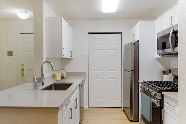 Renovated Package I bath with white cabinetry, beige quartz countertops, white tile backsplash, stainless steel appliances, and hard surface flooring
