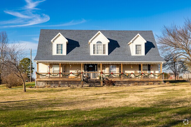 A 2 story farm home with a large porch and dormers sits on a large plot of land in W Fayette.
