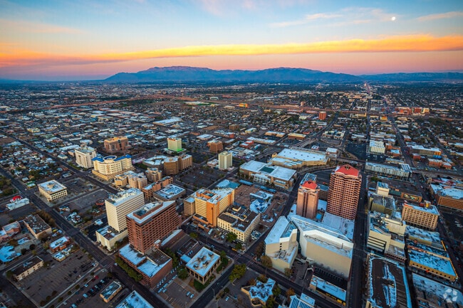 Downtown Albuquerque at sunset with the Sandia Mountains and a moonrise in the distance.