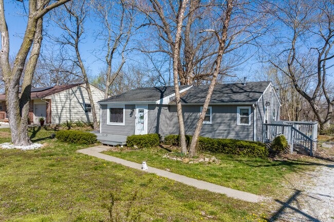 A cozy single-story Craftsman style home in Maple Park, surrounded by mature trees and a simple front walkway.