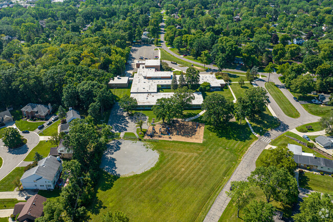 Aerial of school shows the building, open fields, playground, and other aspects in Farmington.