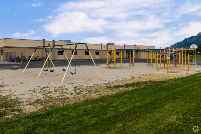 A swings and colorful jungle gym sit on sandy ground at Green Acres Elementary School.