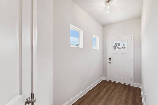 The entrance to the Carlisle home featuring rich hardwood-style flooring and crisp white walls.