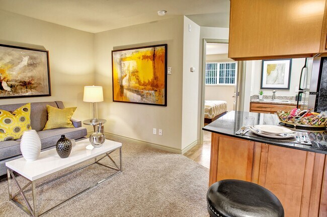 A living room with couch, coffee table, and view into the kitchen