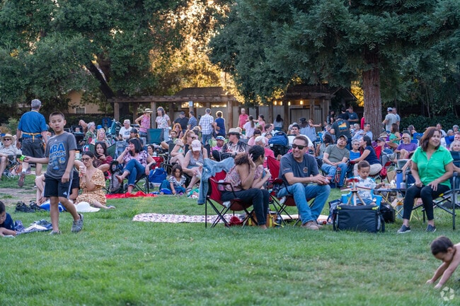 Families gather on the lawn, enjoying a vibrant Music in the Park evening filled with fun.