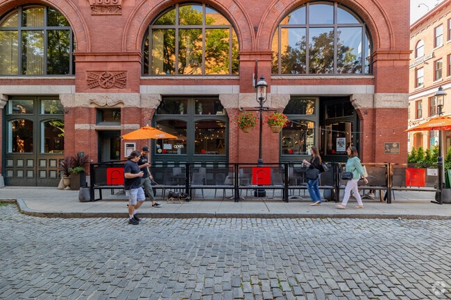 People walk down cobblestone streets in downtown Lowell.