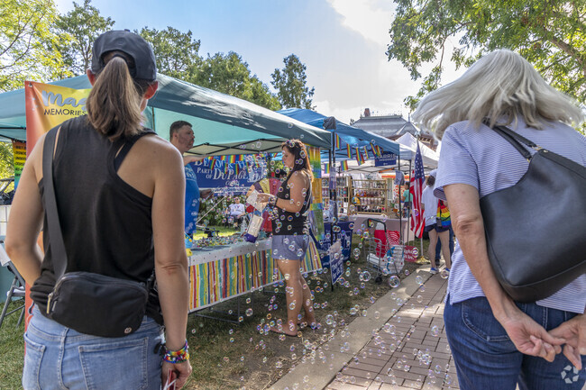 Bubbles glisten in the light as people listen to a person's cause at Naper Pride Fest 2024.