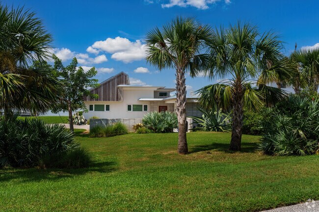 Throughout the front yard of this North Beach home, mature palm trees and shrubs are featured.
