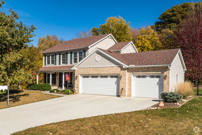 Colonial style home features a front porch and green window shutters in Twin Grove.