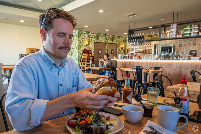 A customer enjoying a brunch burger at the Popping Yolk Cafe in Hacienda Heights