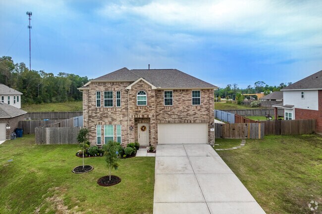 A two-story, Colonial-style home with a manicured lawn and attached garage in Woodbranch.