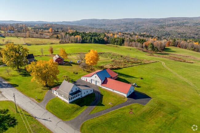 A farmhouse and red-roofed barn in South Barre has expansive farm land with minimal trees.