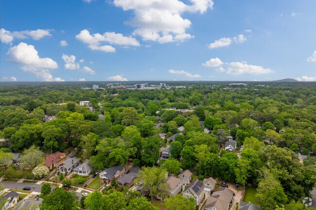 The lush tree canopy of Oakhurst stretches across the horizon, with charming homes nestled beneath and the distant cityscape offering a reminder of the neighborhood’s close-knit feel and urban convenience.