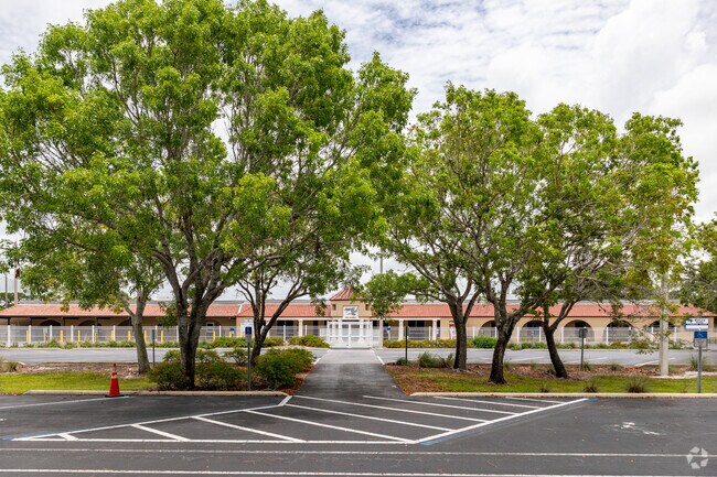 Naples Park Elementary School is adorned with large trees in the front parking lot.