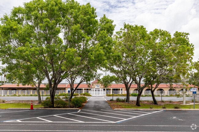 Naples Park Elementary School is adorned with large trees in the front parking lot.