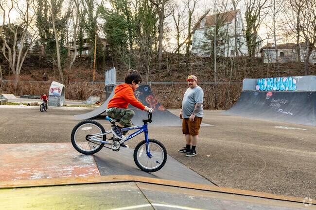 A Father teaches his Son how to have some fun on his bike at Sharen Skate Park.