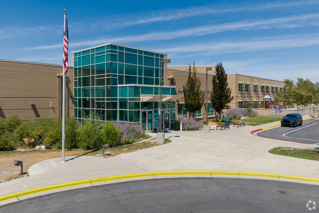 Granger Elementary School has a beautiful two-story teal glass entrance next to a flag.