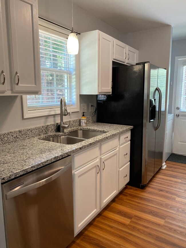 Kitchen has granite counter tops, white cabinets, garbage disposal and stainless appliances including dishwasher and refrigerator.