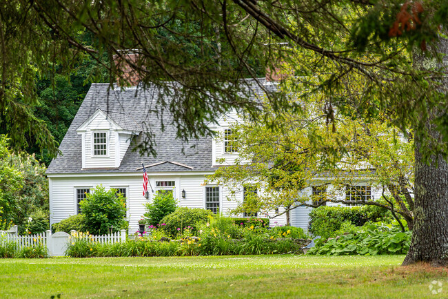 A beautiful Cape Cod styled home peaks through the surrounding landscaping in Gilmanton, NH.