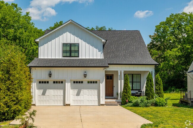A typical new build craftsman home boasts a two car garage, lush grass, and gabled roofs in the Radnor neighborhood.