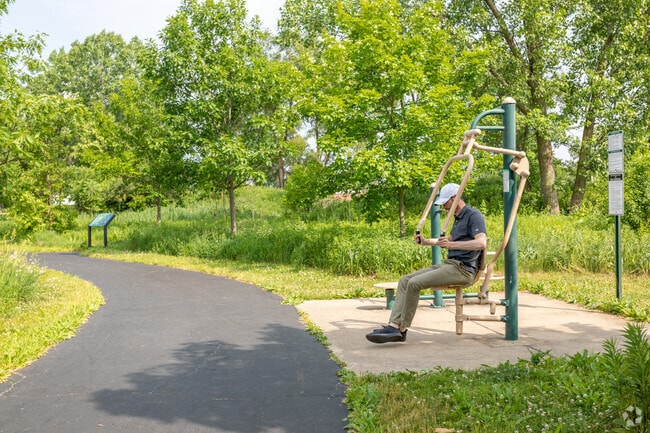 A York Center resident uses public fitness equipment at Knolls Park on a summer day.