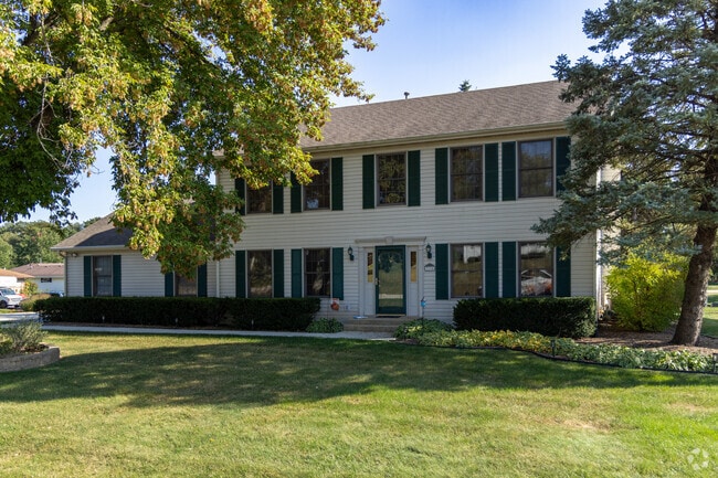 A beautiful Colonial home framed by trees and greenery, blending tradition with timeless appeal.