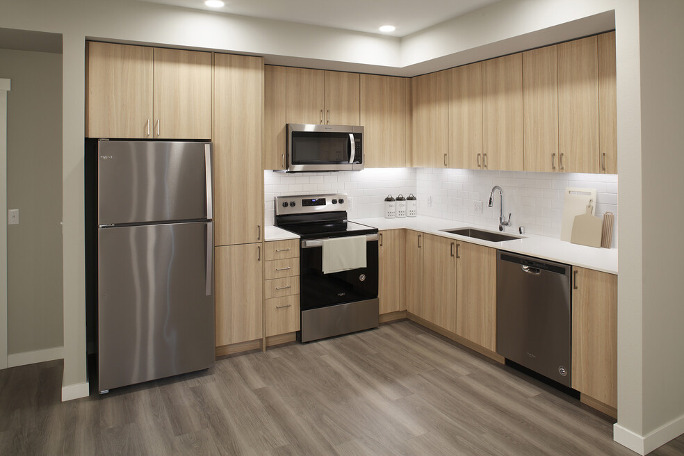 Phase II - Scheme D Kitchen with oak cabinetry, white tile backsplash, stainless steel appliances, white quartz countertops, and hard surface flooring