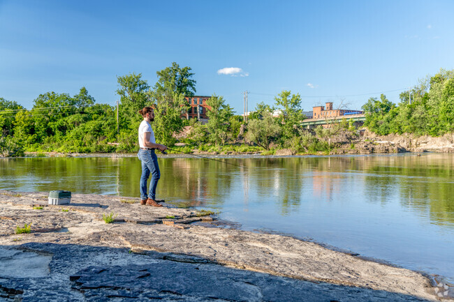 A person fishes on the rocks at Salmon Hole in Riverside.