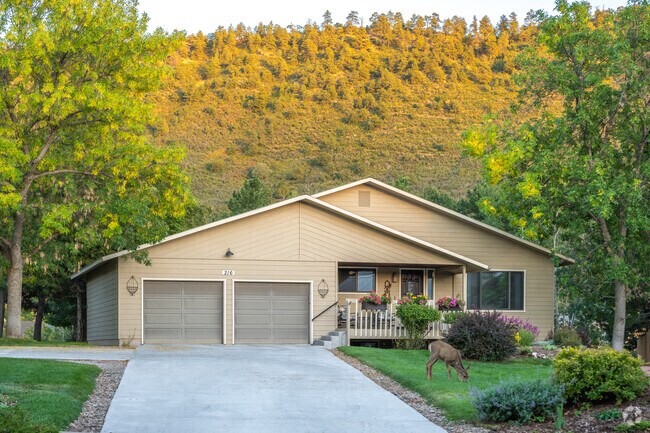 A deer munches on the front lawn of this Craftsman style home at sunset.