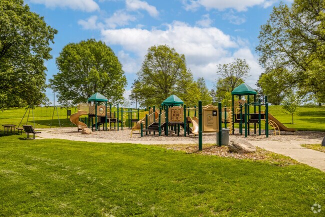 The playground at Thomas Mitchell Park is surrounded by flowers and whimsical mushroom sculptures.