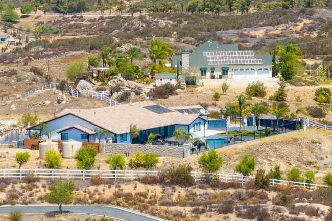 Elegant residential estate featuring a spacious home, landscaped grounds, and a private pool nestled among mature trees.