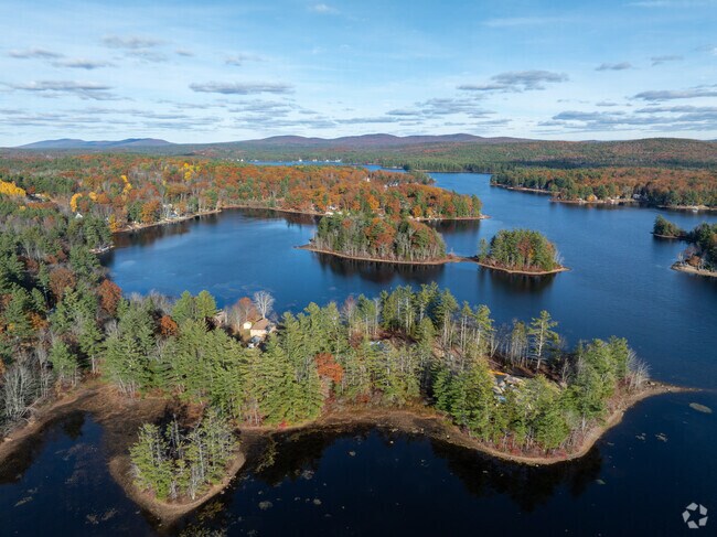 A breathtaking aerial view of Lake Monomonac in Rindge, New Hampshire, surrounded by colorful autumn forests and tranquil island inlets.