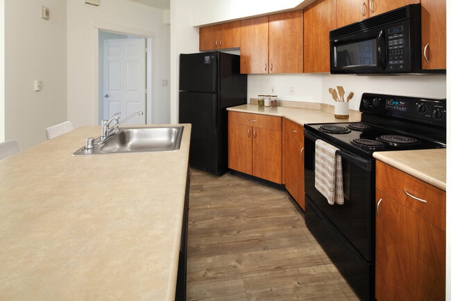 Classic Package I kitchen with laminate countertops, oak cabinetry, black appliances, and hard surface flooring