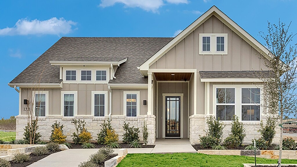 Elegant stone facade, lush landscaping, and gabled roof grace this Spring Creek residence.