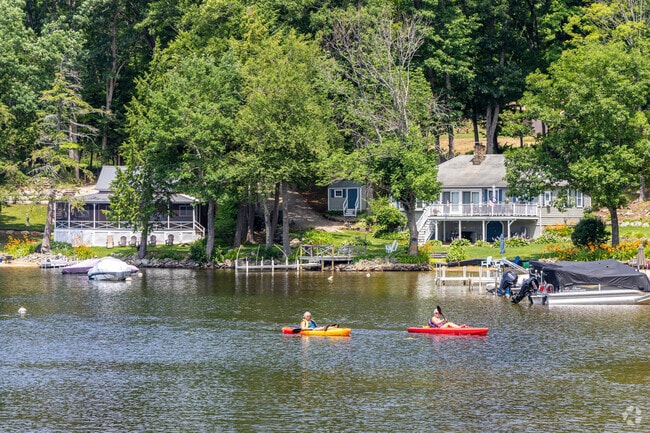 A pair of kayakers on the pass by a row of lakeside homes on the Upper Suncook in Barnstead.