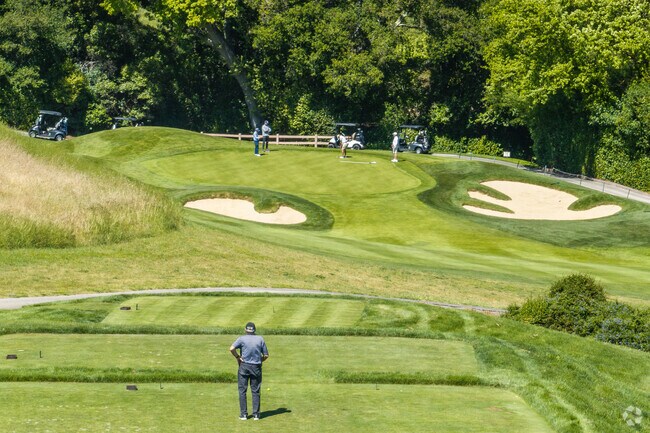 A man waits to tee off while the group in front of him finishes the hole.