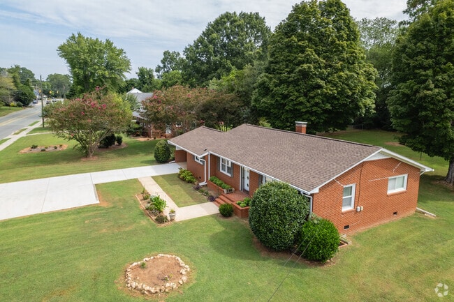 Aerial view of a brick ranch style house sitting on a large plot of land.