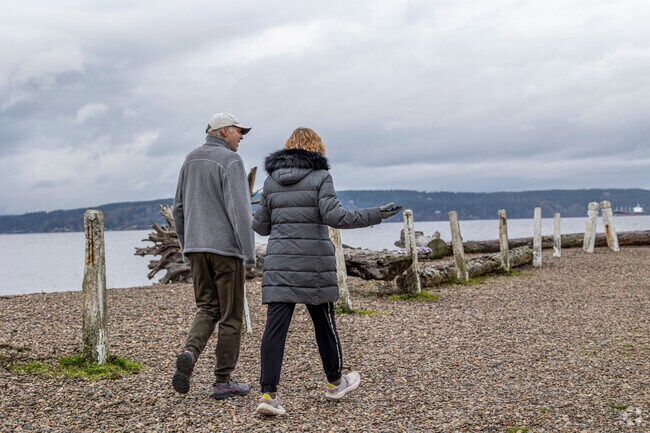 A couple walks the coastline of Browns Point Lighthouse Park.