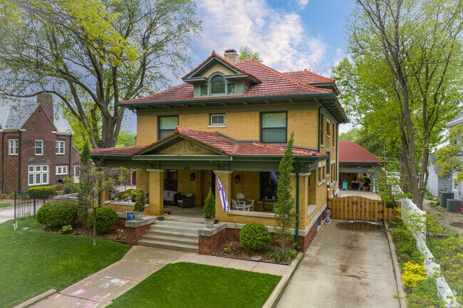 Three-story yellow brick home with red clay rooftop in College Hill neighborhood.